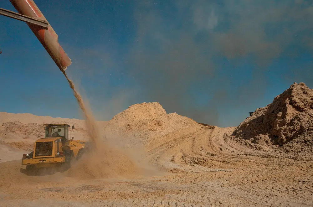 Loader moving biomass feedstock at an industrial yard